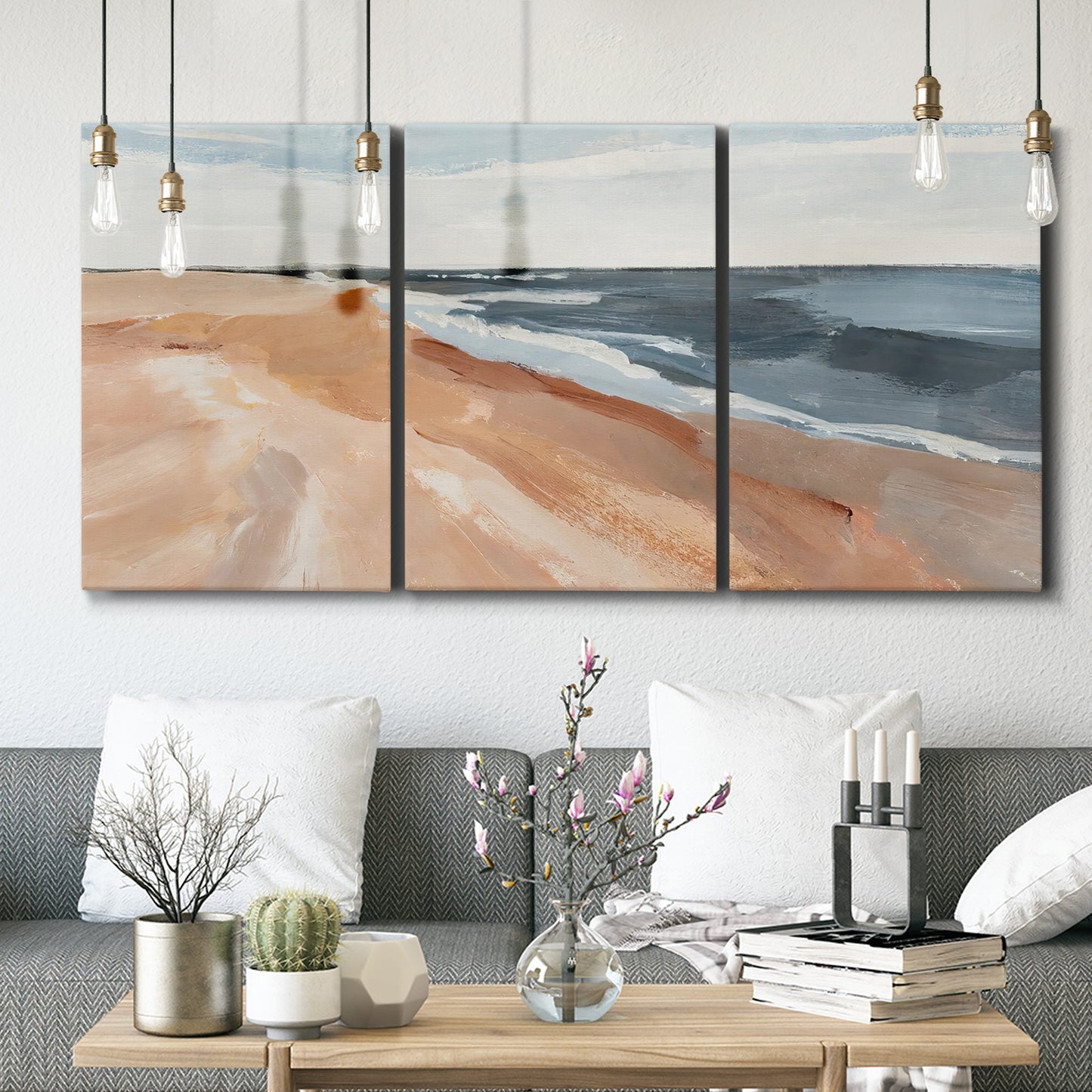 Three-panel canvas wall art featuring abstract coastal beach composition, displayed in a modern living room above seating.