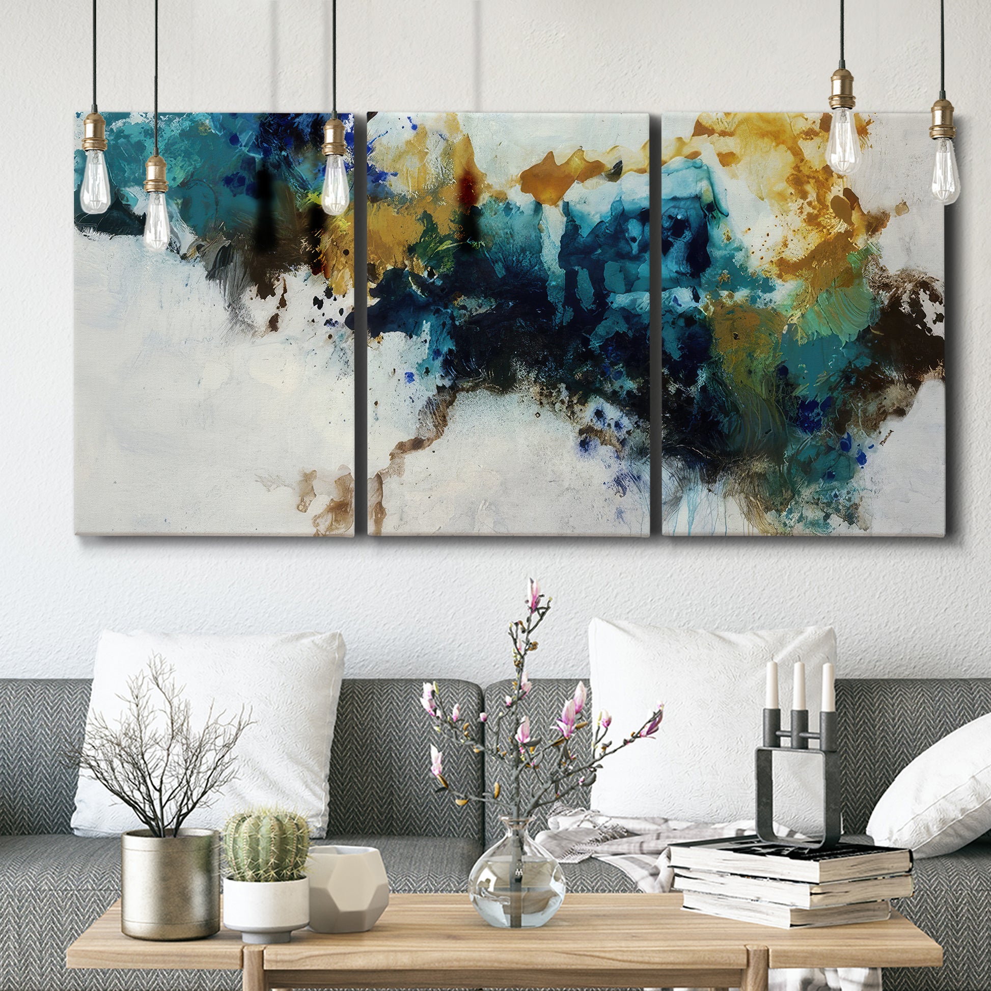 Three-panel canvas wall art featuring teal abstract paint splatter, displayed in a modern living room above seating.