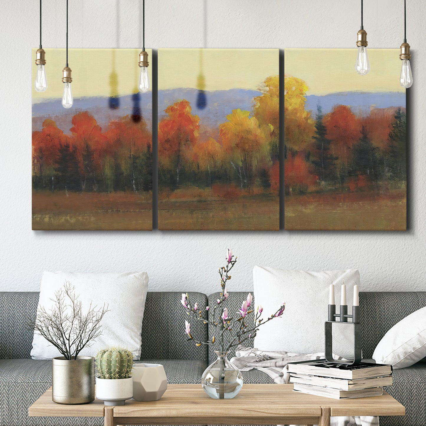 Three-panel canvas wall art featuring autumn landscape changing foliage, displayed in a modern living room above seating.
