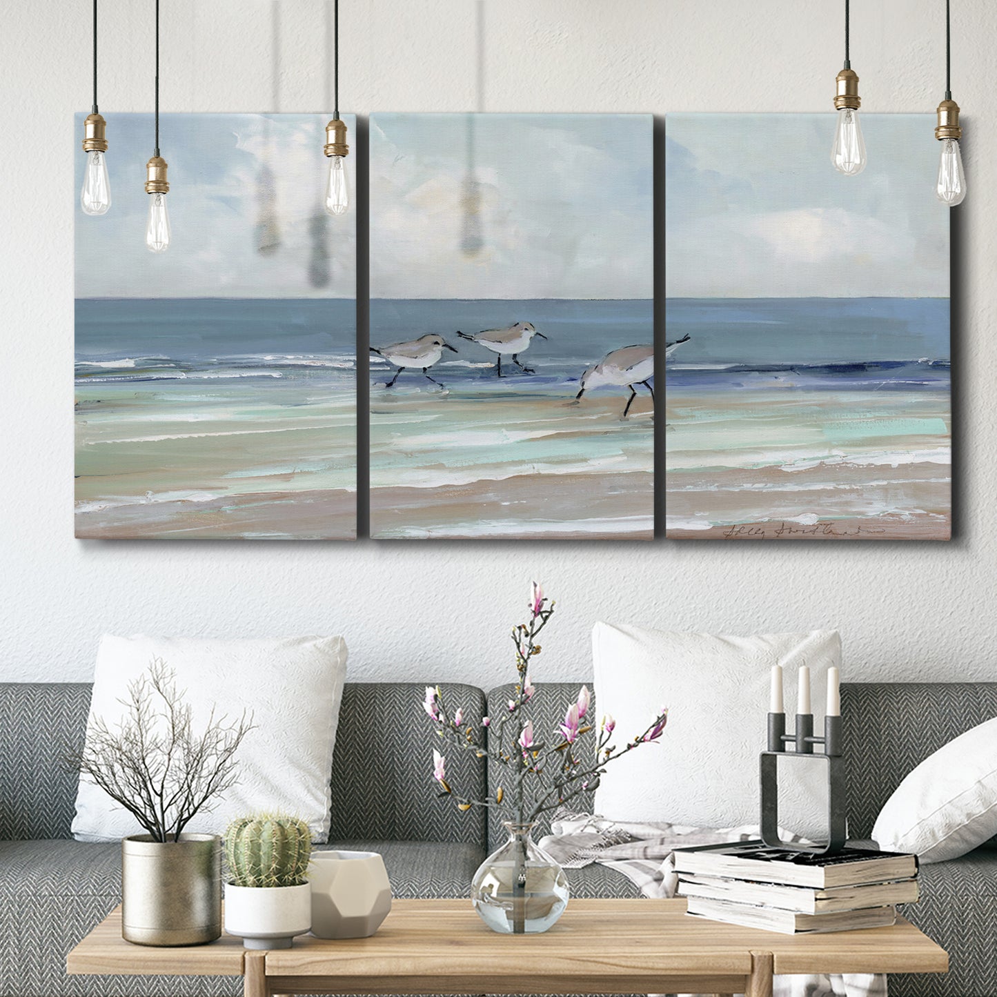 Three-panel canvas wall art featuring shore birds searching along beach, displayed in a modern living room above seating.