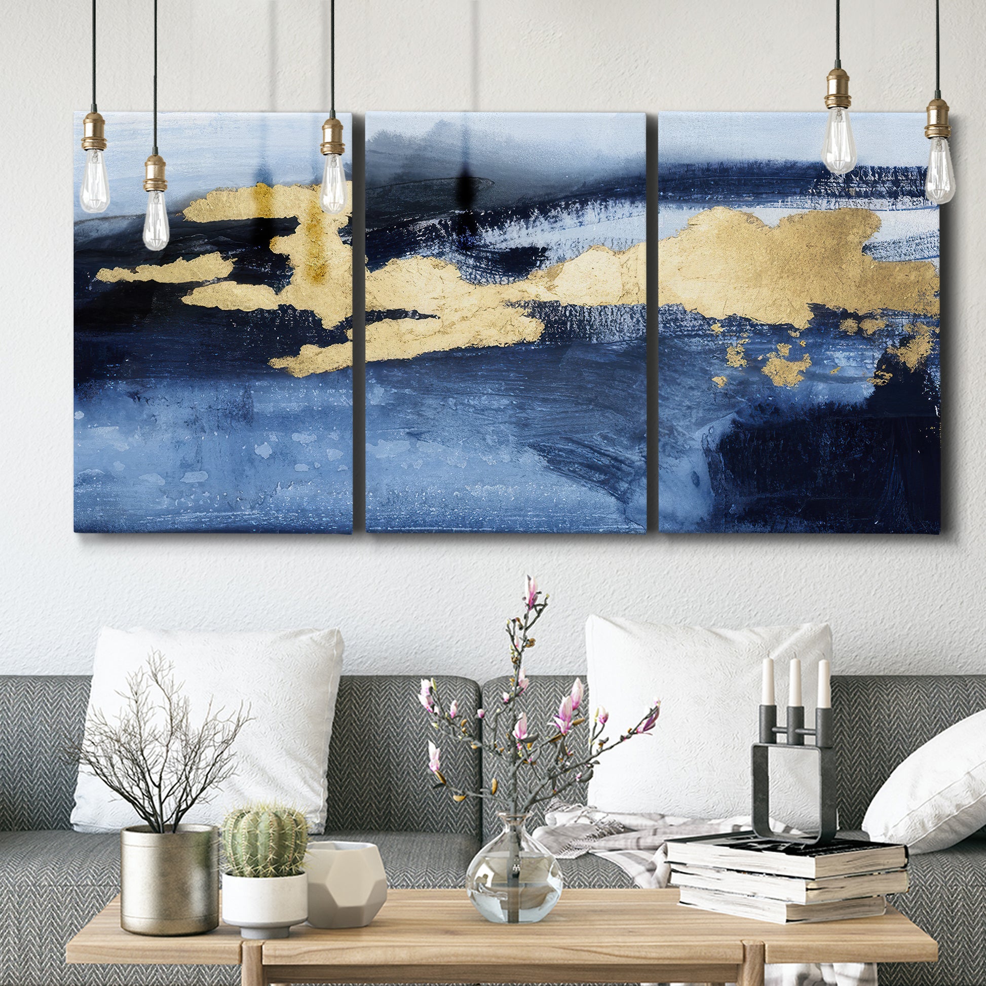 Three-panel canvas wall art featuring coastal shoreline with warm light, displayed in a modern living room above seating.