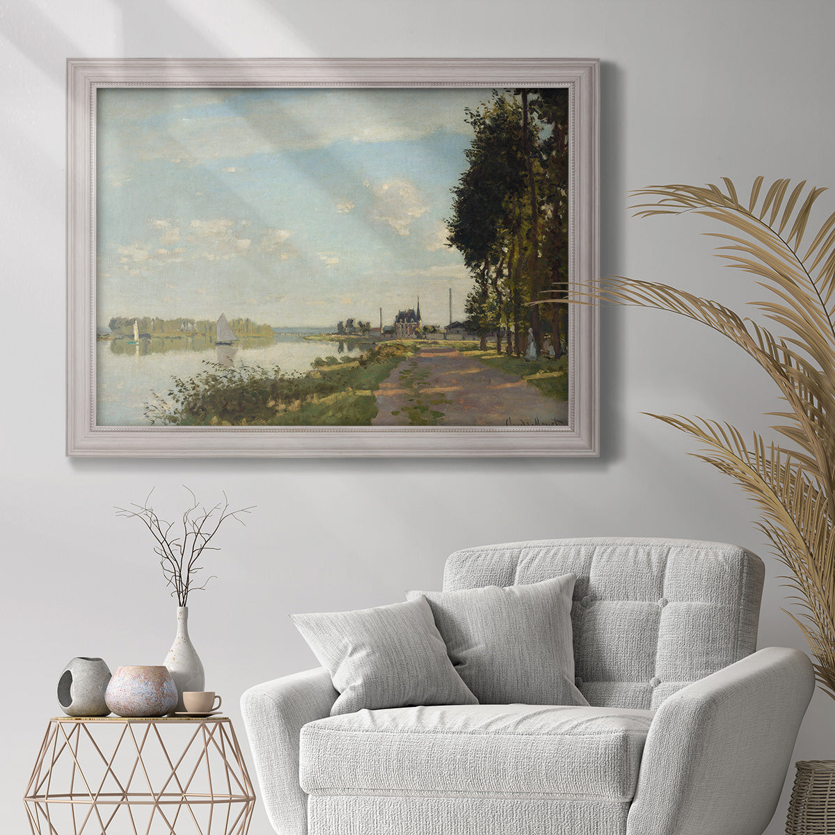 Impressionist river scene with red boats by Claude Monet in an ornate weathered white frame displayed in a bright interior setting.