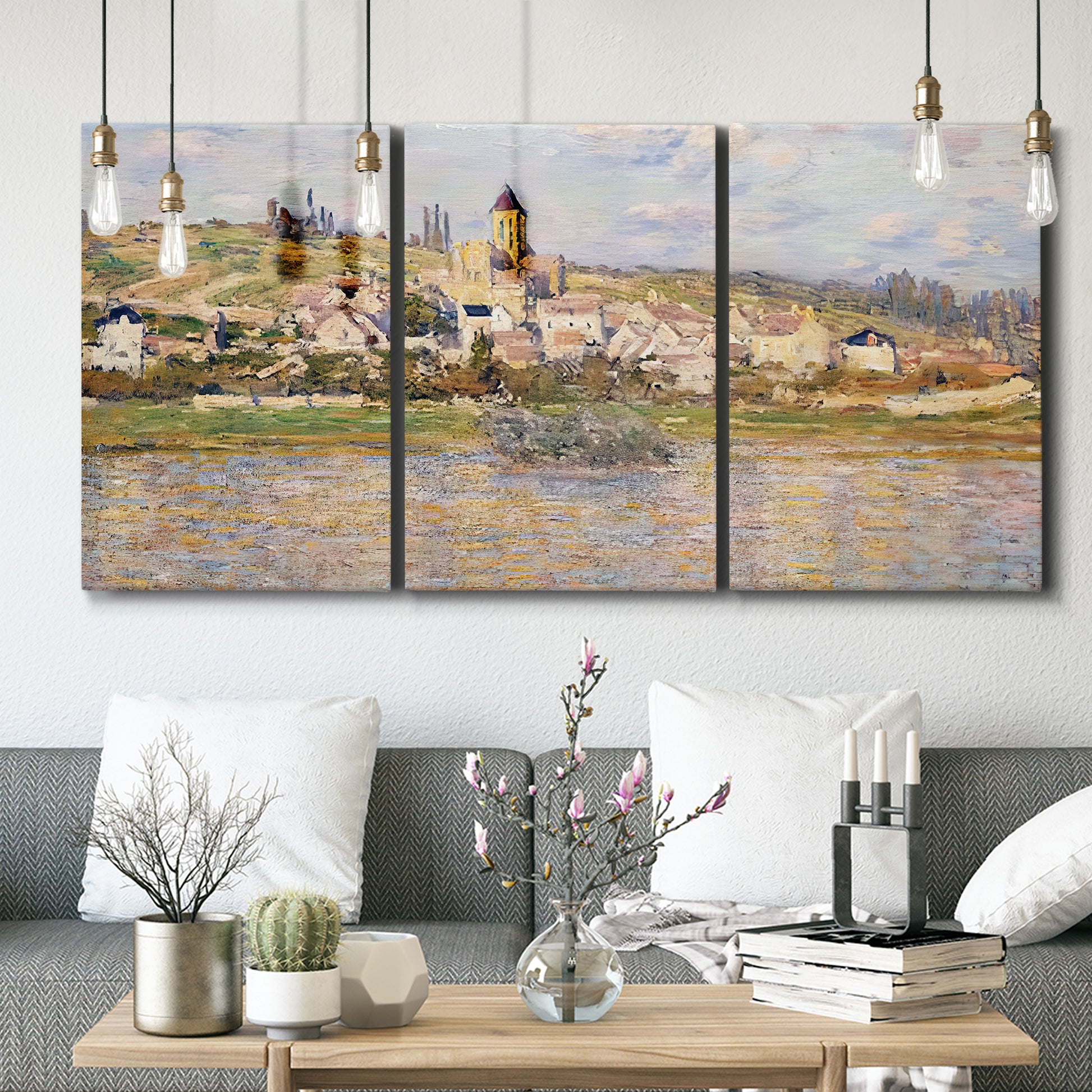 Three-panel canvas wall art featuring village overlooking river valley, displayed in a modern living room above seating.
