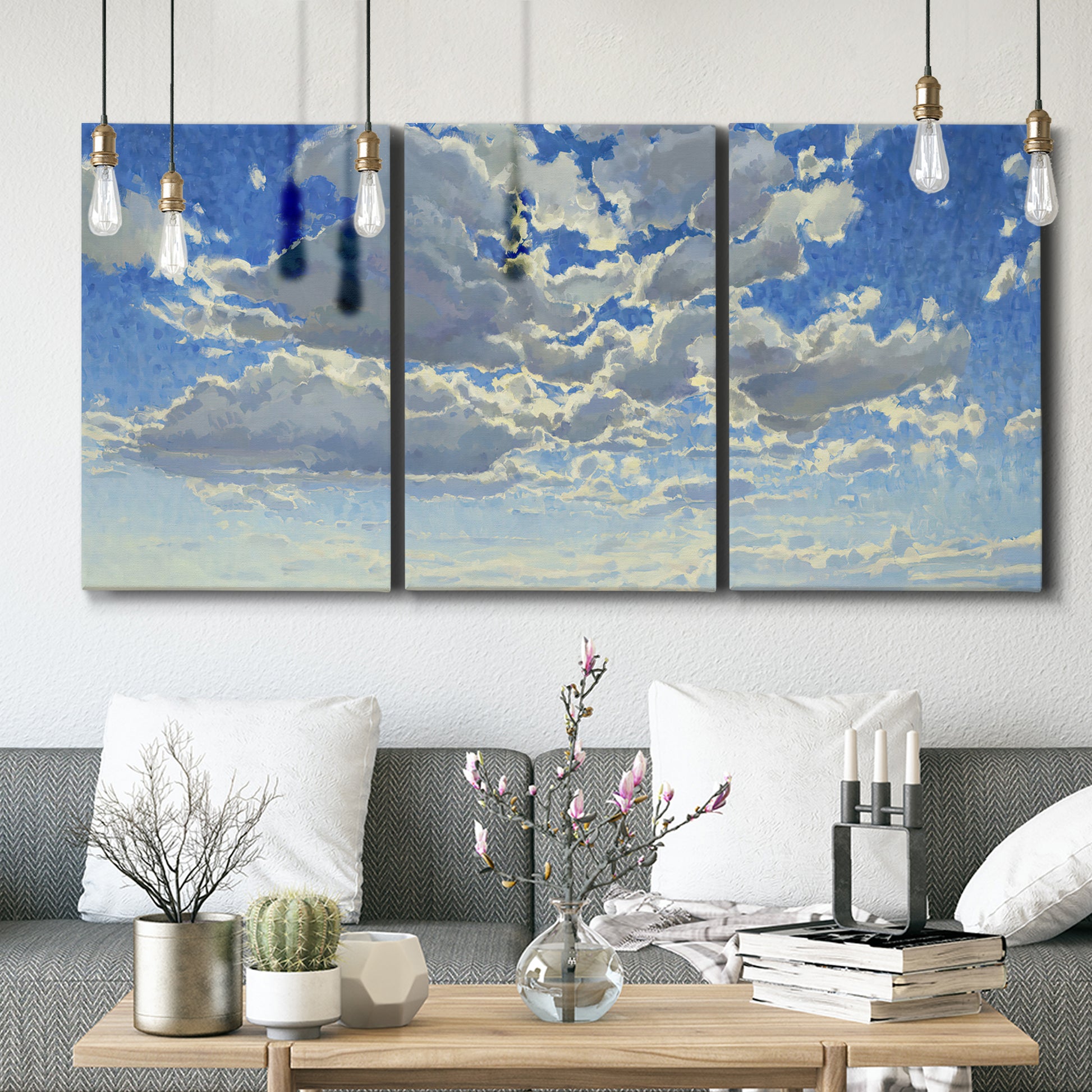 Three-panel canvas wall art featuring whimsical cloud filled sky landscape, displayed in a modern living room above seating.