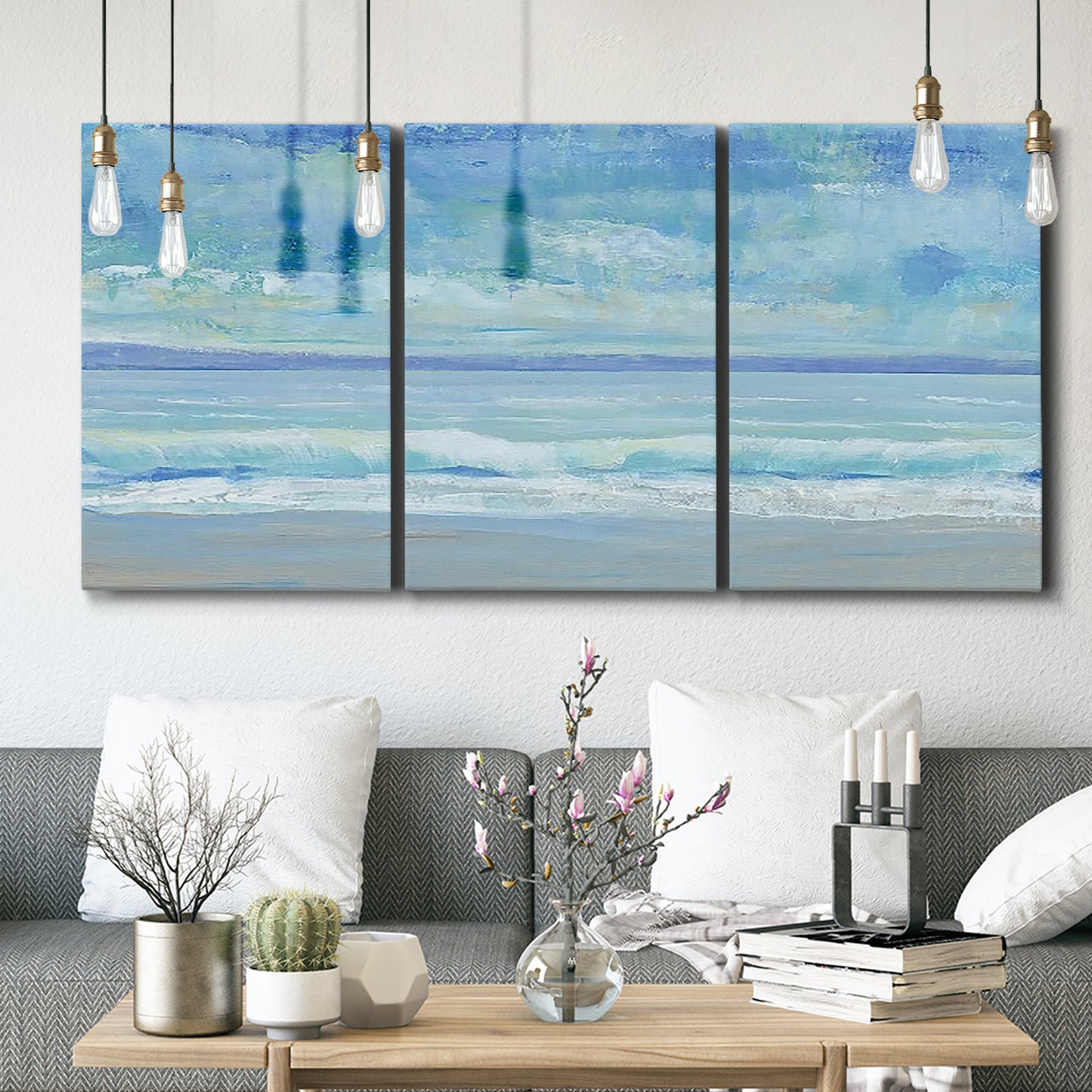 Three-panel canvas wall art featuring rolling ocean surf along shoreline, displayed in a modern living room above seating.