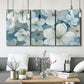 Three-panel canvas wall art featuring soft white floral abstraction, displayed in a modern living room above seating.