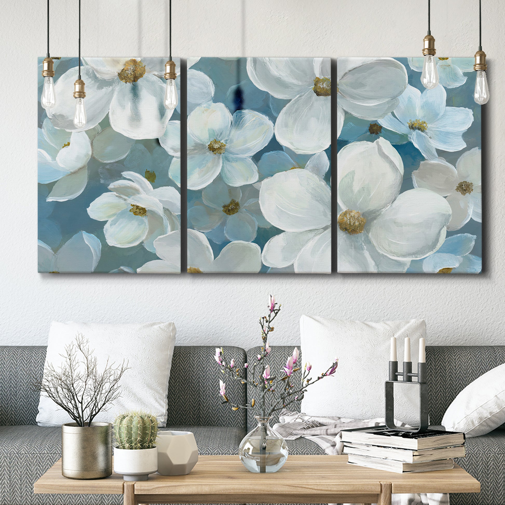 Three-panel canvas wall art featuring soft white floral abstraction, displayed in a modern living room above seating.
