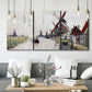 Three-panel canvas wall art featuring windmills beside calm water, displayed in a modern living room above seating.