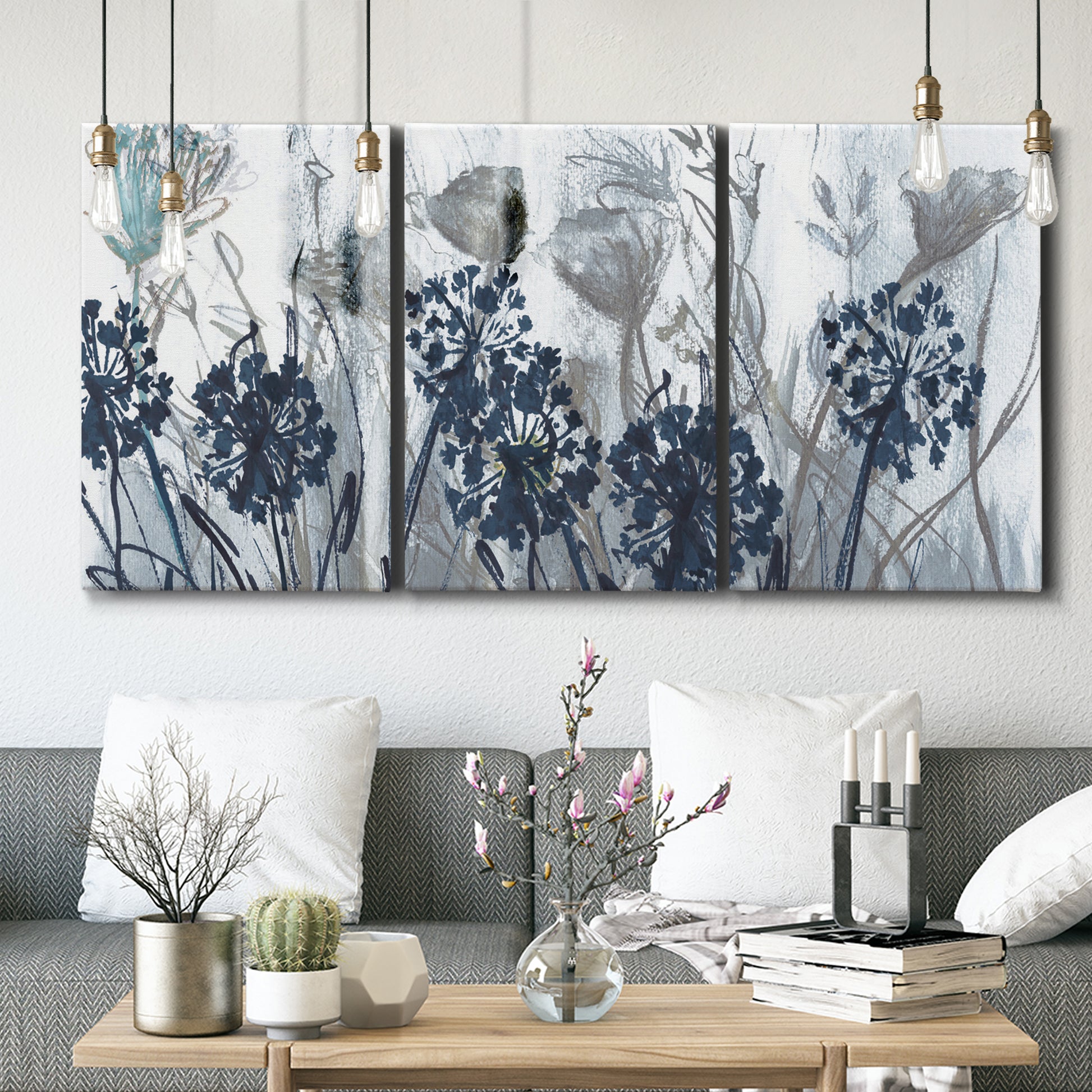 Three-panel canvas wall art featuring indigo floral abstraction, displayed in a modern living room above seating.