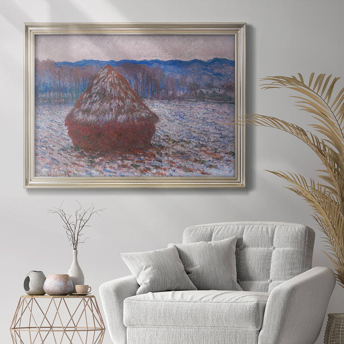 Impressionist single haystack landscape by Claude Monet in an ornate champagne frame displayed in a bright interior setting.