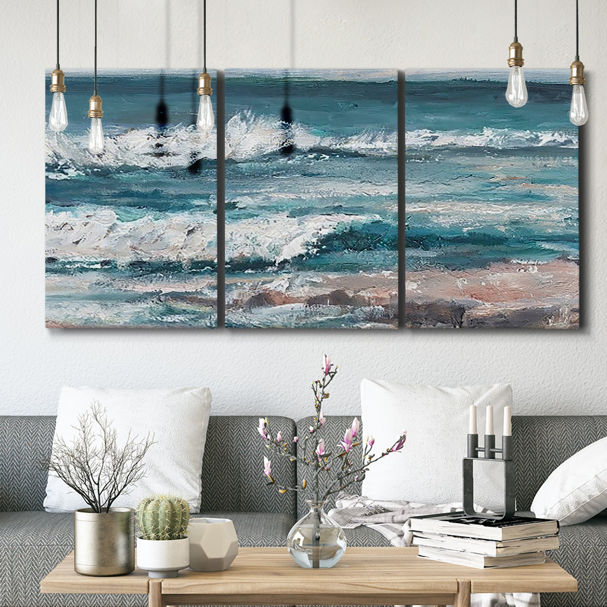 Three-panel canvas wall art featuring crashing ocean waves along shoreline, displayed in a modern living room above seating.