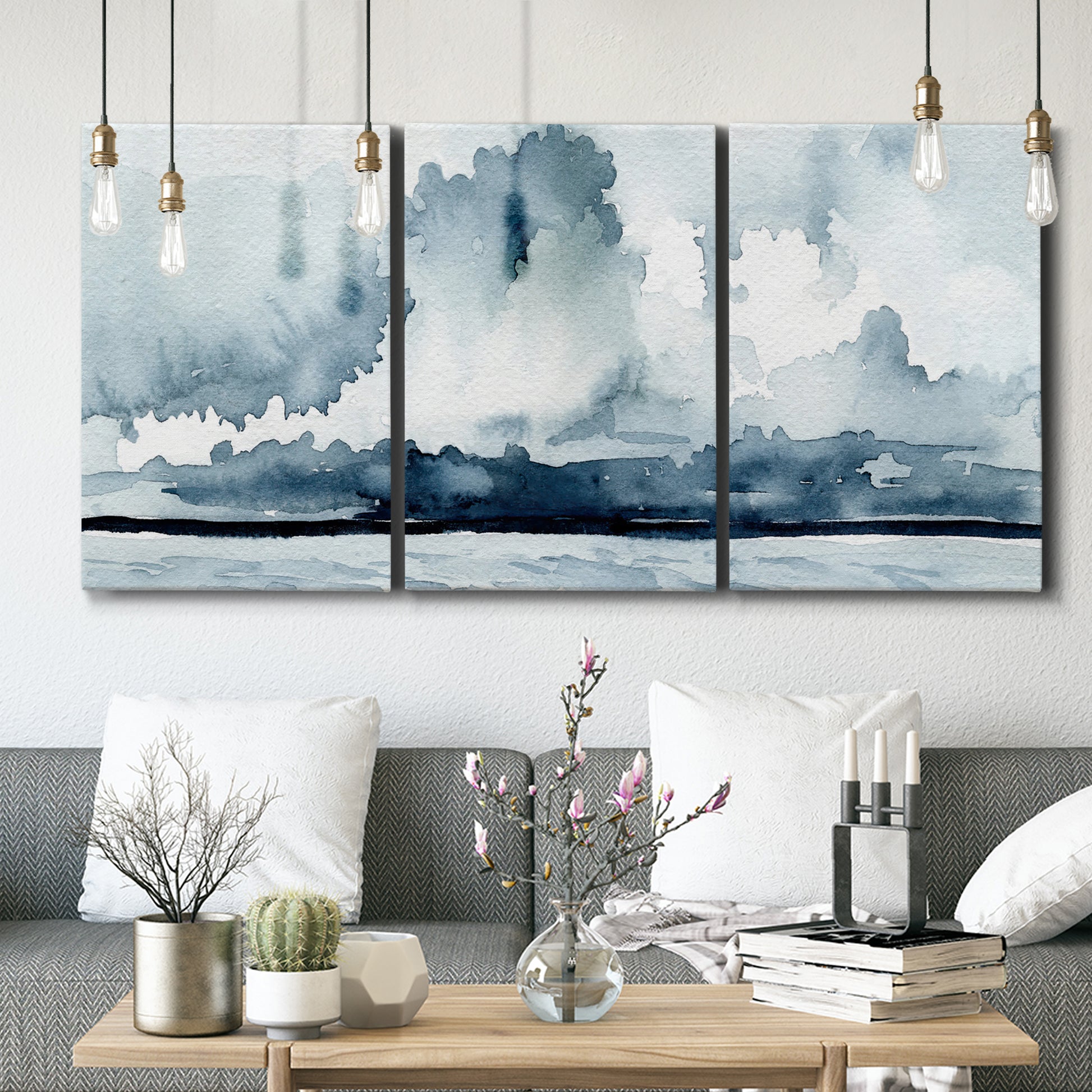 Three-panel canvas wall art featuring abstract rainstorm watercolor, displayed in a modern living room above seating.