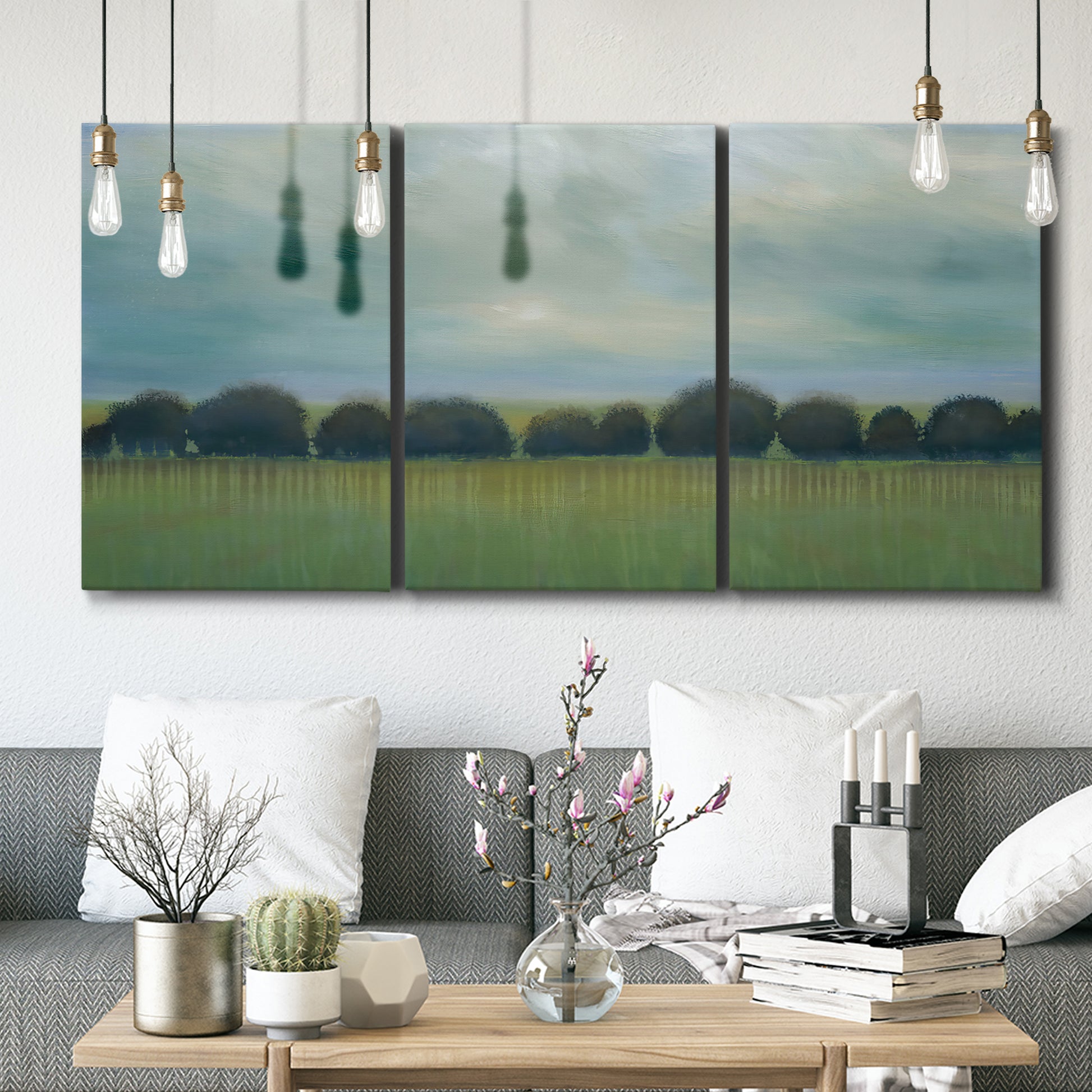 Three-panel canvas wall art featuring rolling green pastoral fields, displayed in a modern living room above seating.