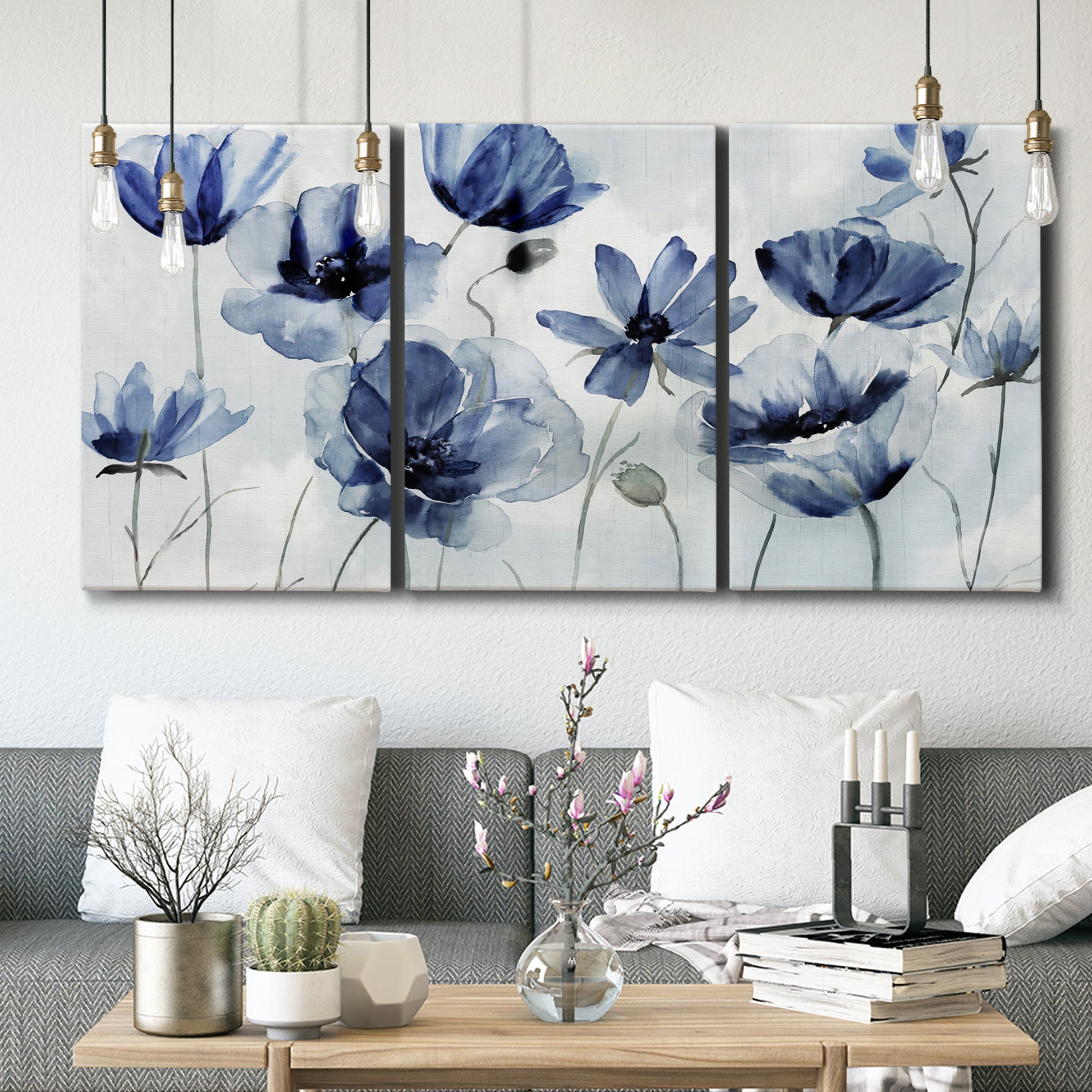 Three-panel canvas wall art featuring indigo floral blossoms awakening, displayed in a modern living room above seating.