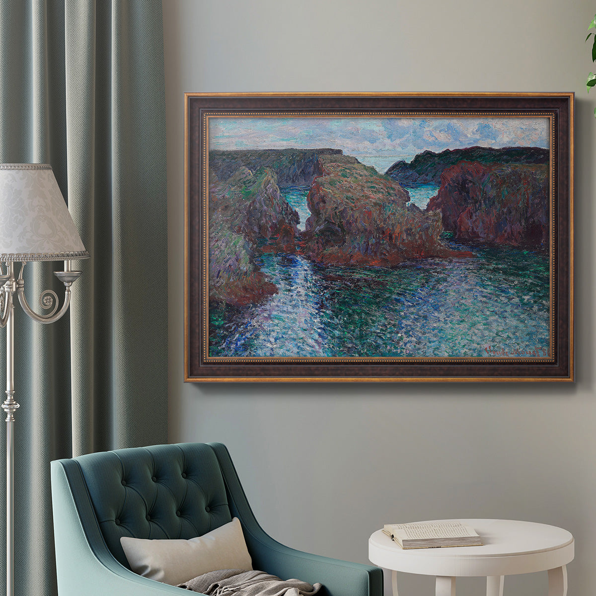 Impressionist rocky seascape by Claude Monet in an ornate bronzed mahogany wood frame displayed in a bright interior setting.