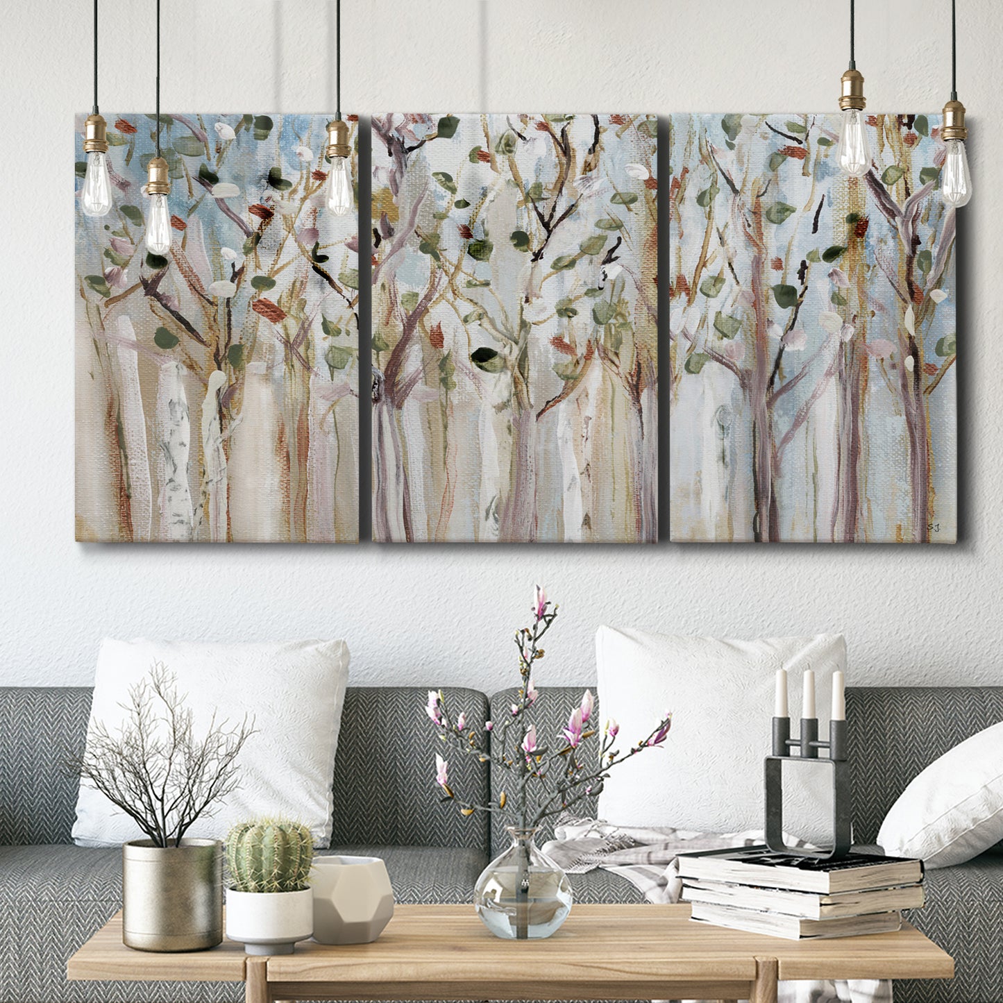 Three-panel canvas wall art featuring bare birch trees in winter forest, displayed in a modern living room above seating.