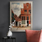 Realist city street scene by Johannes Vermeer in an ornate champagne frame displayed in a dark-toned interior setting.