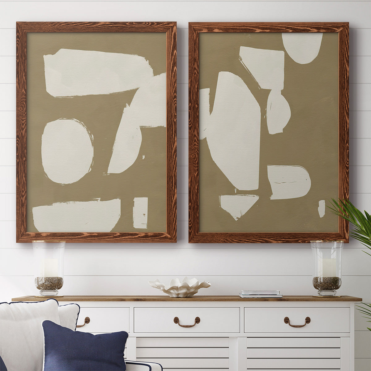 Set of two maple barnwood framed canvas prints depicting a coordinated art pair of irregular white cutout-like shapes on taupe grounds rendered as bold minimalist shape abstracts above a dining room sideboard.