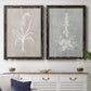 Set of two black barnwood framed canvas prints depicting a coordinated art pair of white botanical silhouettes on softly weathered neutral backgrounds rendered as rustic minimalist botanical prints above a dining room sideboard.