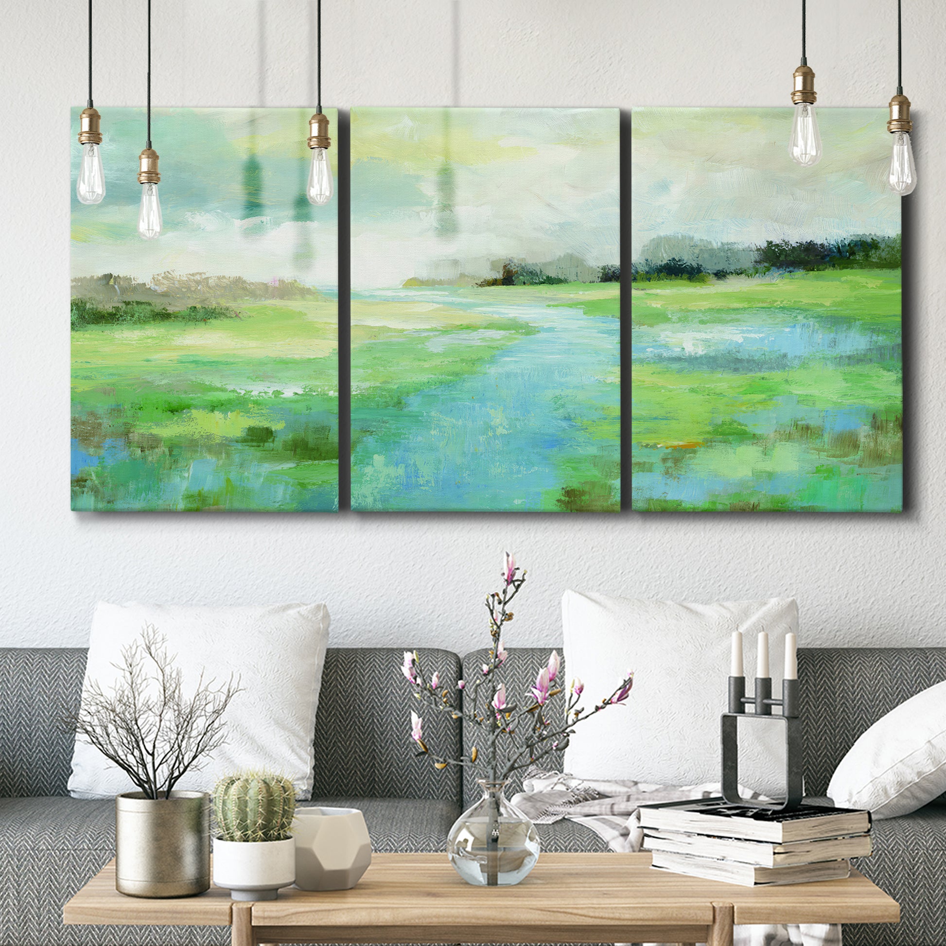 Three-panel canvas wall art featuring gentle stream winding through trees, displayed in a modern living room above seating.