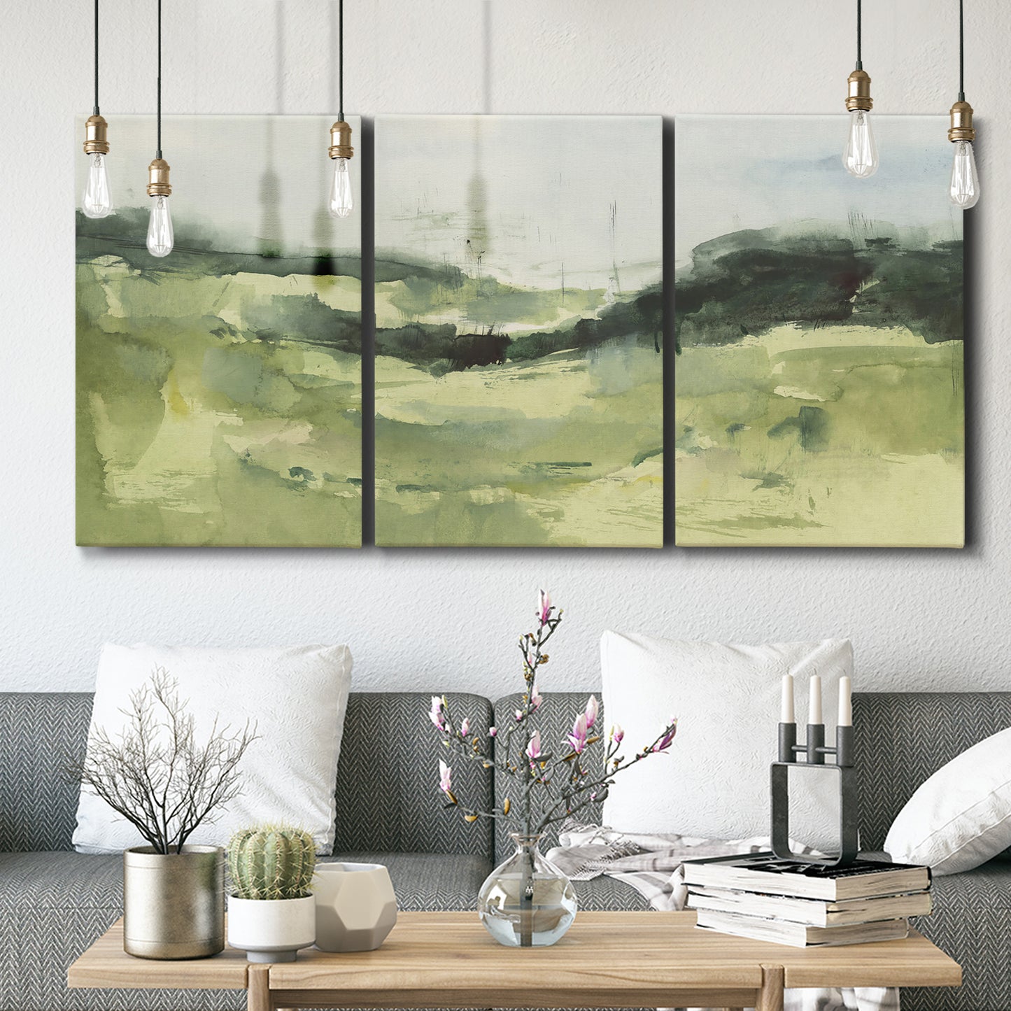 Three-panel canvas wall art featuring rolling hillside countryside landscape, displayed in a modern living room above seating.