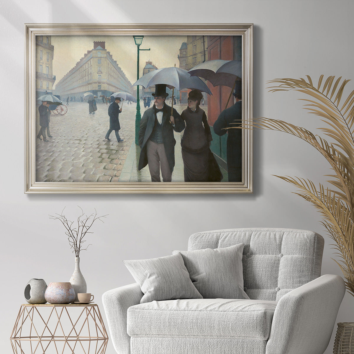 Impressionist urban street scene in the rain by Gustave Caillebotte in an ornate champagne frame displayed in a bright interior setting.