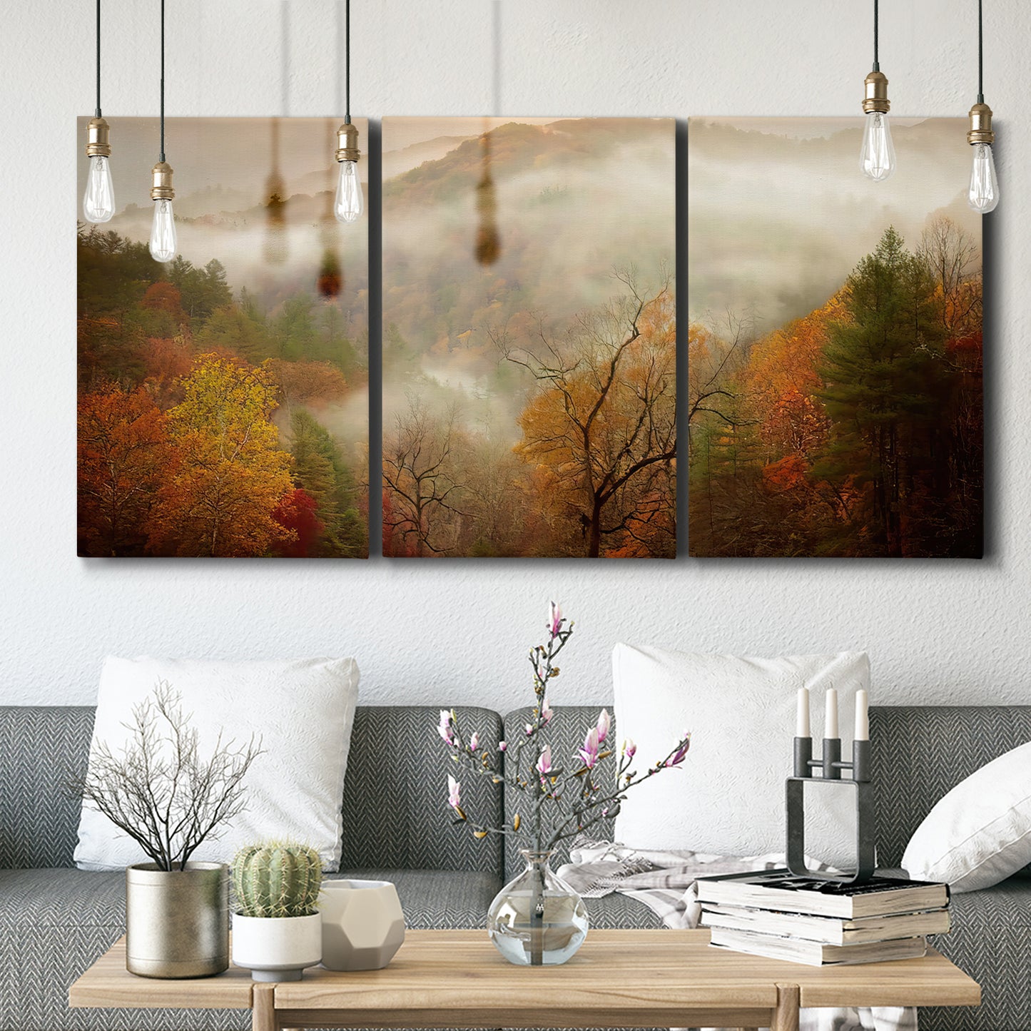 Three-panel canvas wall art featuring misty autumn landscape photograph, displayed in a modern living room above seating.
