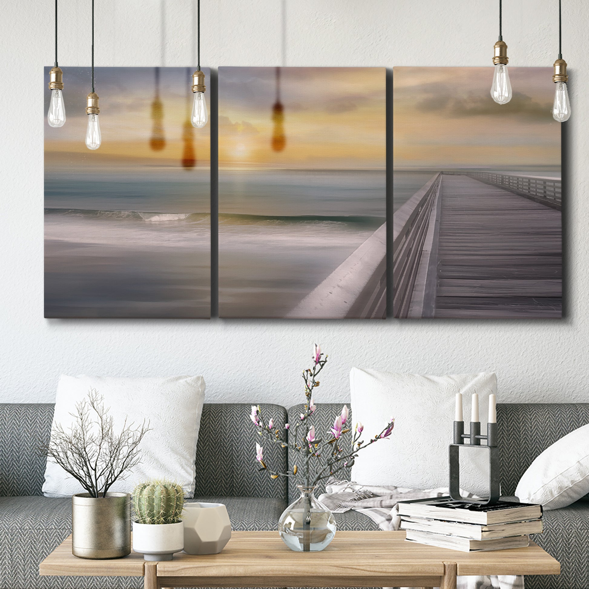 Three-panel canvas wall art featuring tropical beach at sunset photograph, displayed in a modern living room above seating.