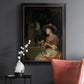 Classical interior scene of a woman weaving flowers by Godfried Schalcken in an ornate black frame with gilded inner detail displayed in a dark-toned interior setting.