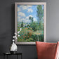 Impressionist pastoral landscape with poppy fields by Claude Monet in an ornate weathered white frame displayed in a dark-toned interior setting.