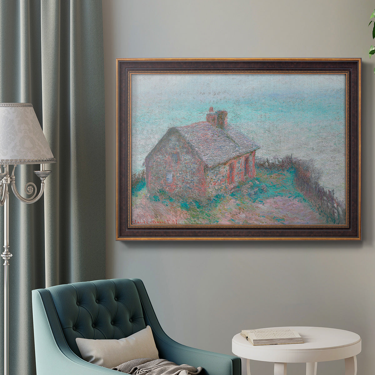 Impressionist coastal building landscape by Claude Monet in an ornate bronzed mahogany wood frame displayed in a bright interior setting.