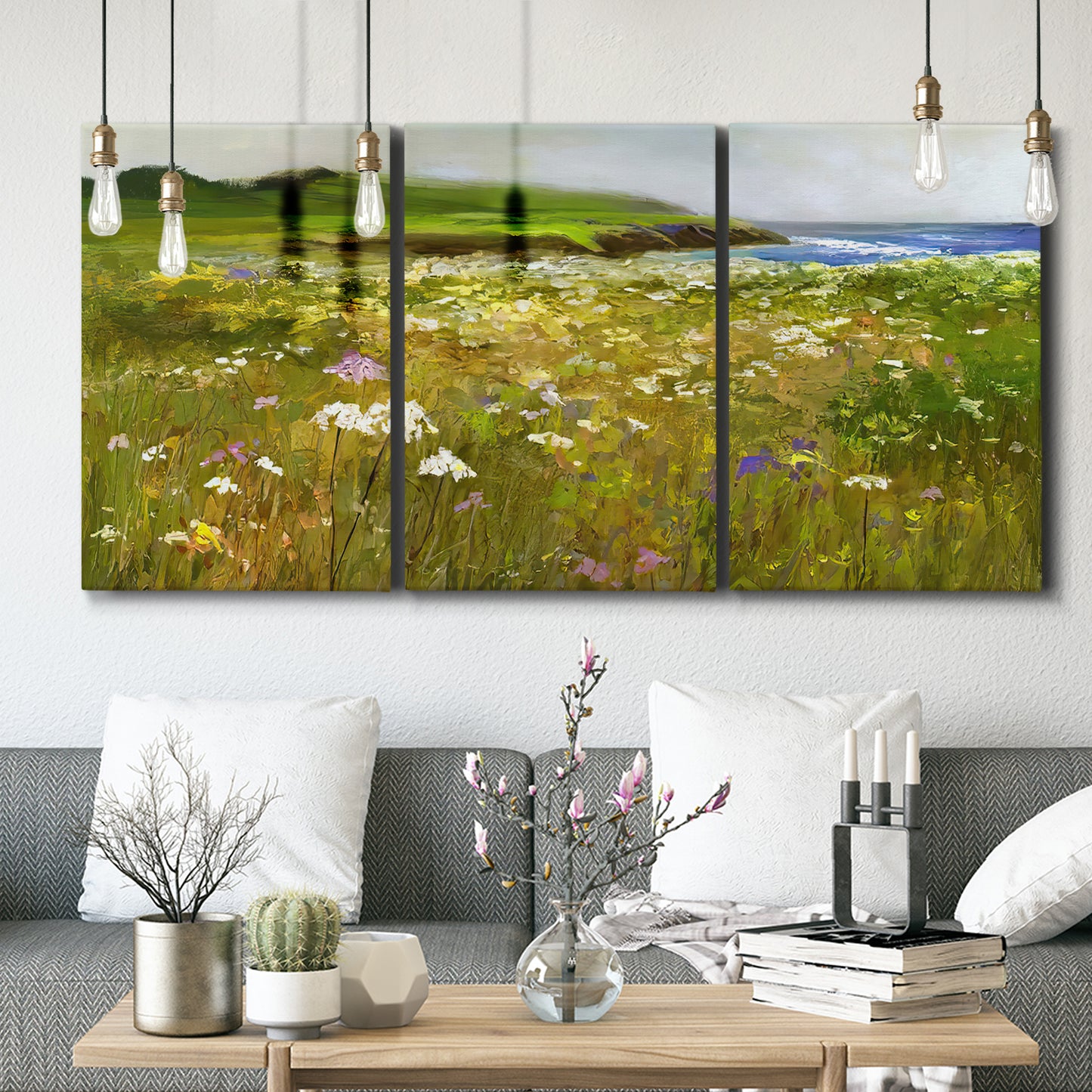 Three-panel canvas wall art featuring rugged coastal cliff landscape, displayed in a modern living room above seating.