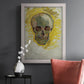 Expressive skull study painting by Vincent van Gogh in an ornate weathered white frame displayed in a dark-toned interior setting.