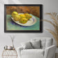 Impressionist still life with lemons by Vincent van Gogh in an ornate black frame with gilded inner detail displayed in a bright interior setting.