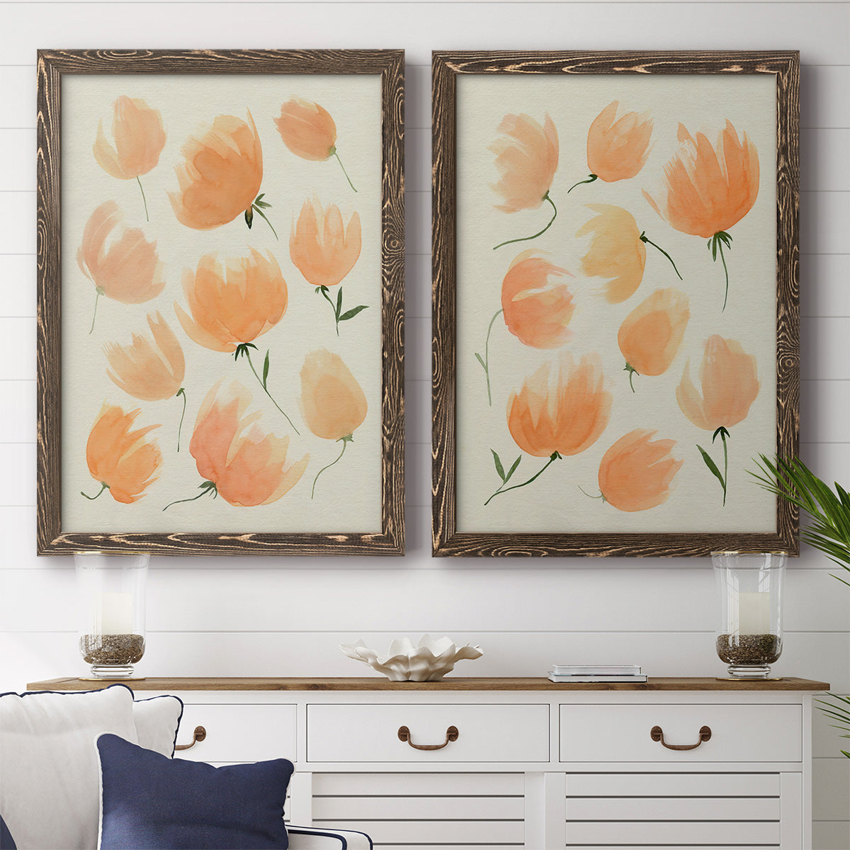 Set of two walnut barnwood framed canvas prints depicting a coordinated art pair of loose peach-orange tulip-like blossoms rendered as airy watercolor floral paintings above a dining room sideboard.