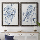 Set of two black barnwood framed canvas prints depicting a coordinated art pair of loose blue flowers and leafy branches rendered as expressive watercolor botanical paintings above a dining room sideboard.