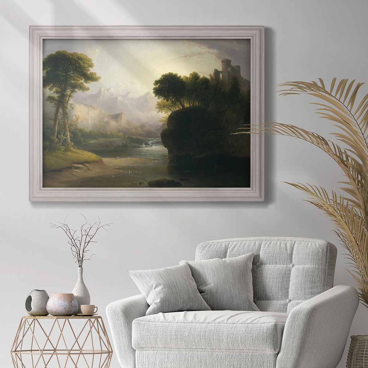 Romantic autumn landscape along the Hudson River by Thomas Doughty in an ornate weathered white frame displayed in a bright interior setting.