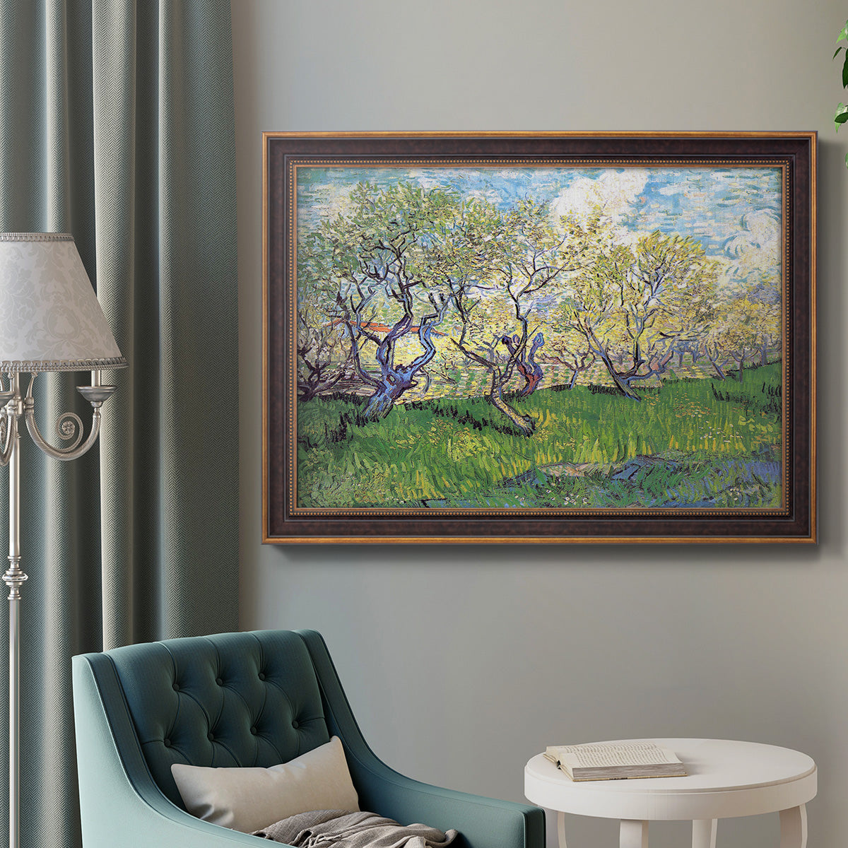 Impressionist spring orchard landscape by Vincent van Gogh in an ornate bronzed mahogany wood frame displayed in a bright interior setting.