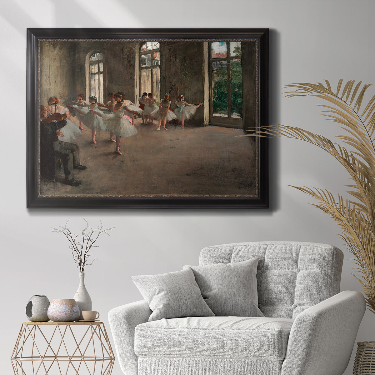 Early impressionist ballet rehearsal painting by Edgar Degas in an ornate black frame with gilded inner detail displayed in a bright interior setting.