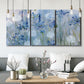 Three-panel canvas wall art featuring delicate watercolor floral blooms, displayed in a modern living room above seating.