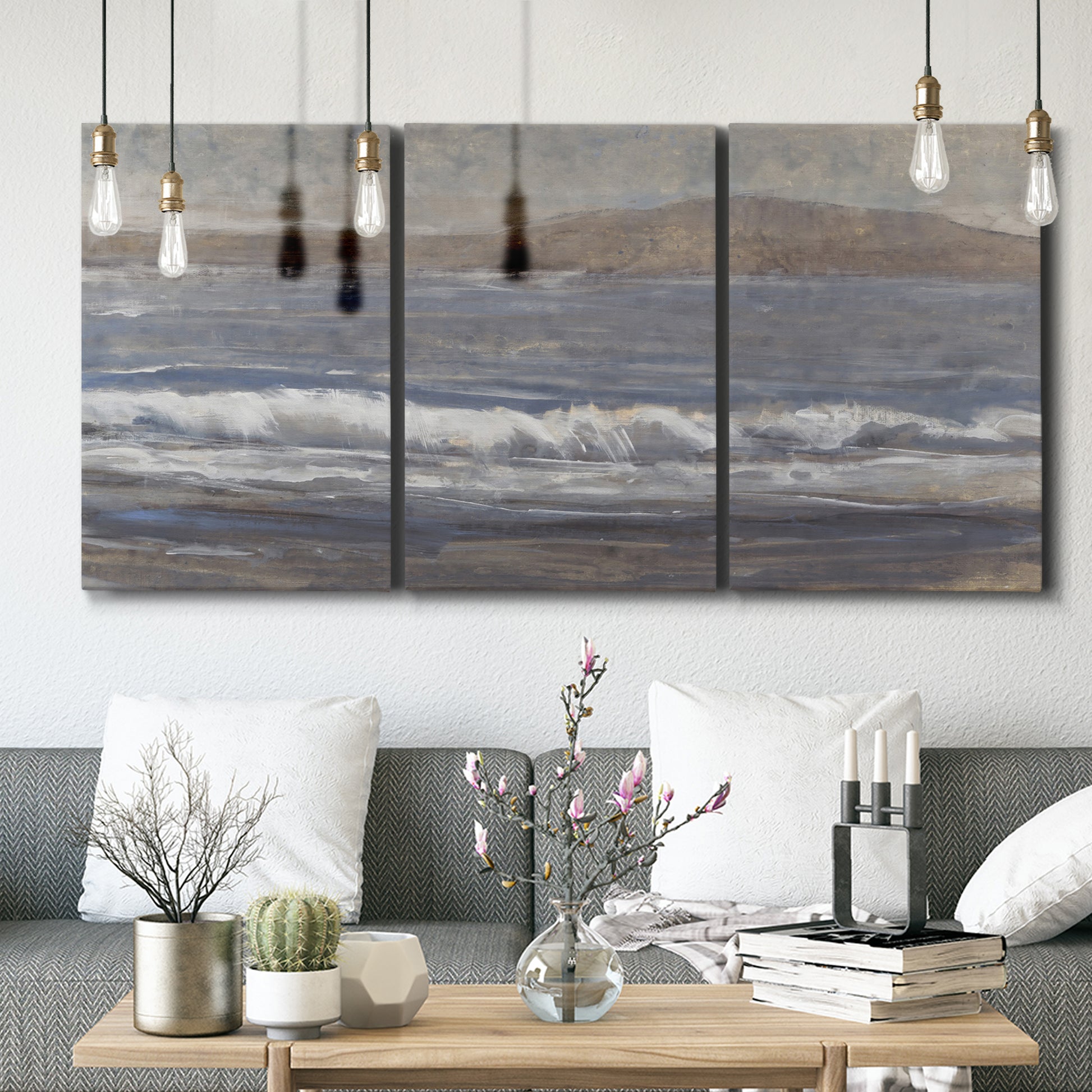 Three-panel canvas wall art featuring shoreline between land and sea, displayed in a modern living room above seating.