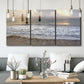 Three-panel canvas wall art featuring calm coastal shoreline seascape, displayed in a modern living room above seating.