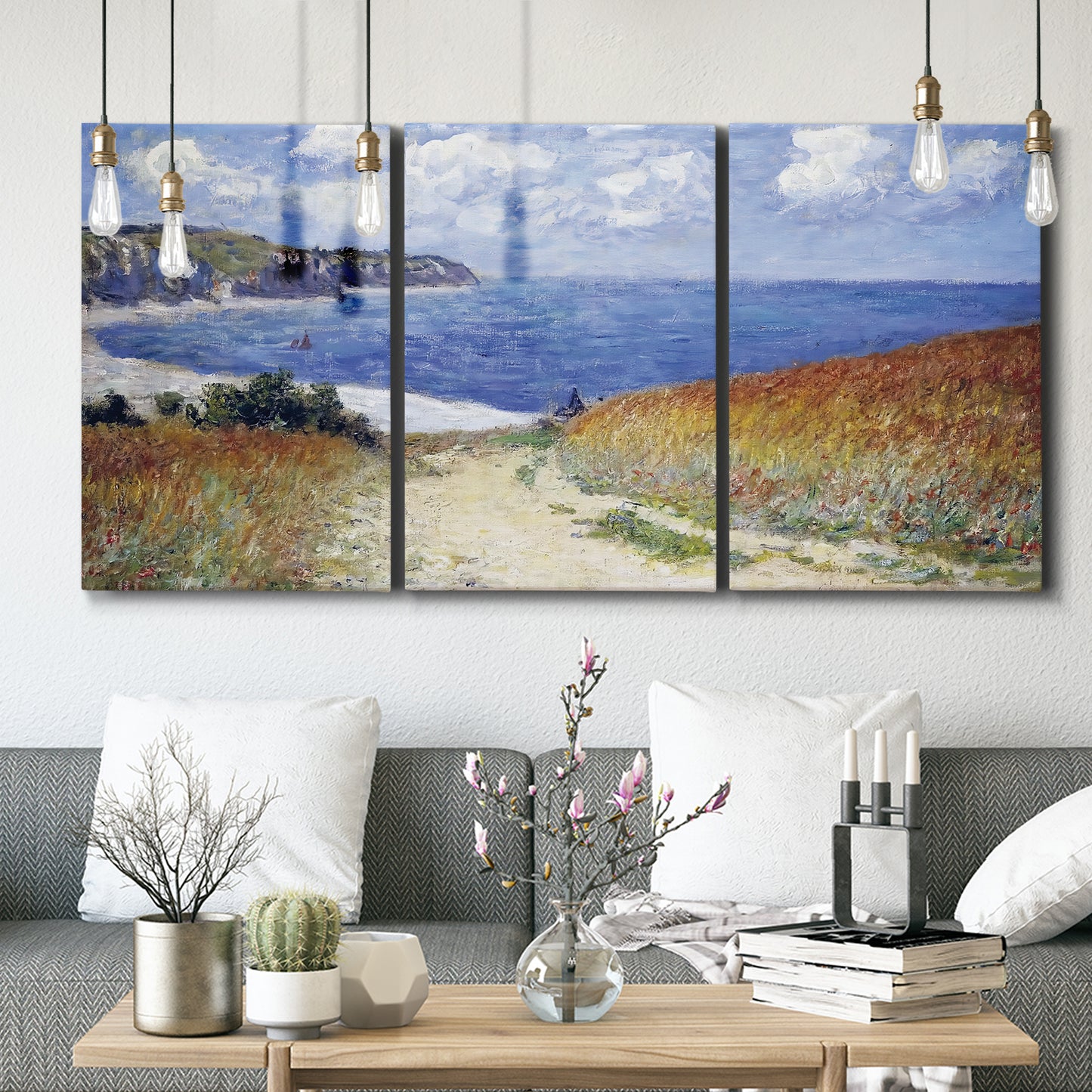 Three-panel canvas wall art featuring coastal path leading to sea, displayed in a modern living room above seating.