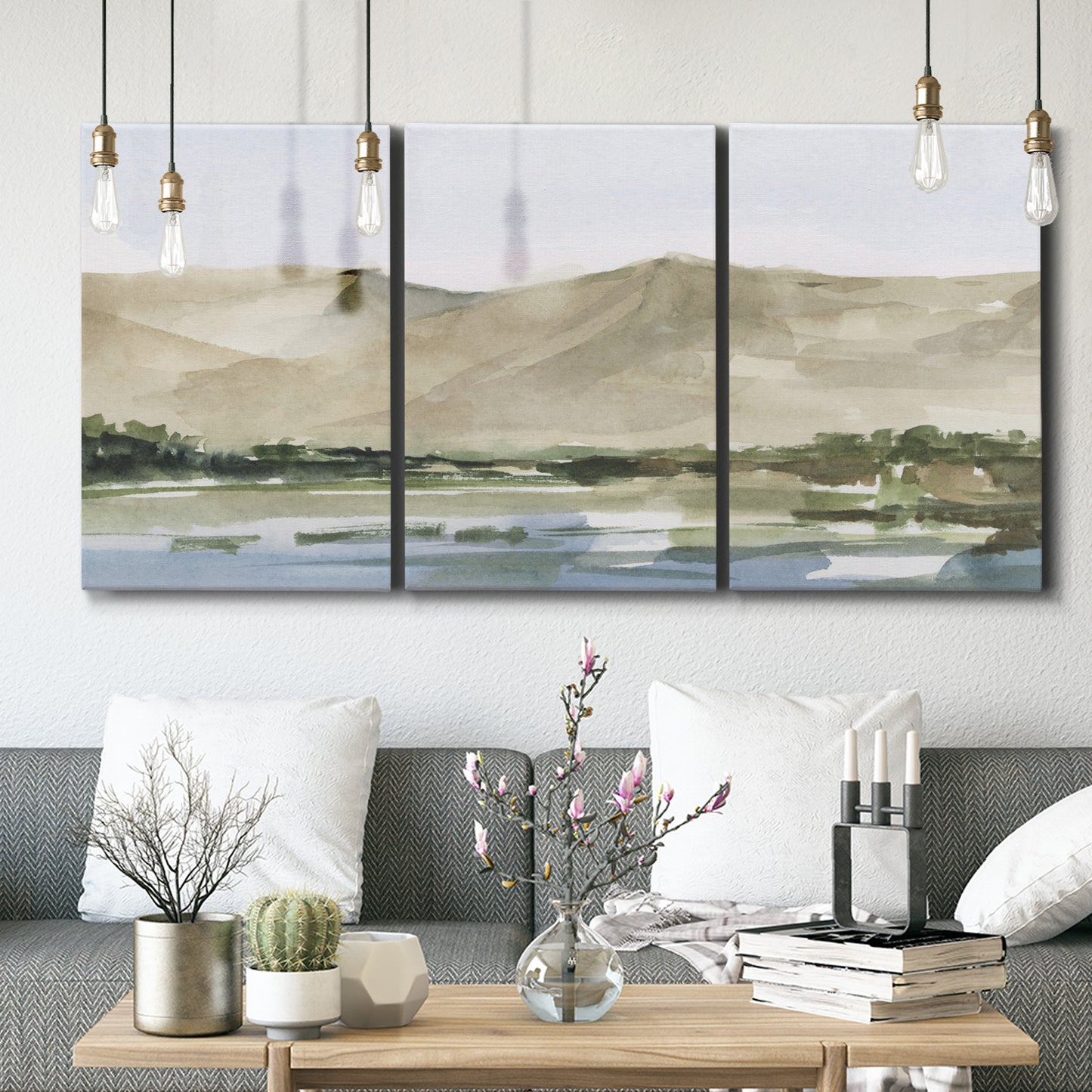 Three-panel canvas wall art featuring desert mountain landscape watercolor, displayed in a modern living room above seating.