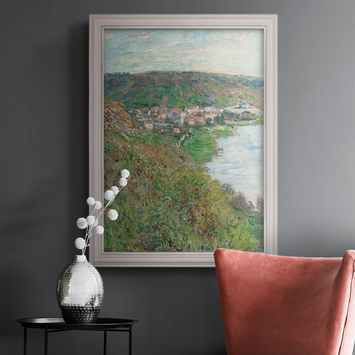 Impressionist landscape view of Vétheuil by Claude Monet in an ornate weathered white frame displayed in a dark-toned interior setting.