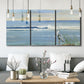 Three-panel canvas wall art featuring sunrise reflecting across bay waters, displayed in a modern living room above seating.