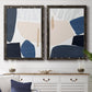 Set of two black barnwood framed canvas prints depicting a coordinated art pair of large navy cream and beige organic geometric shapes rendered as minimalist color-block abstracts above a dining room sideboard.