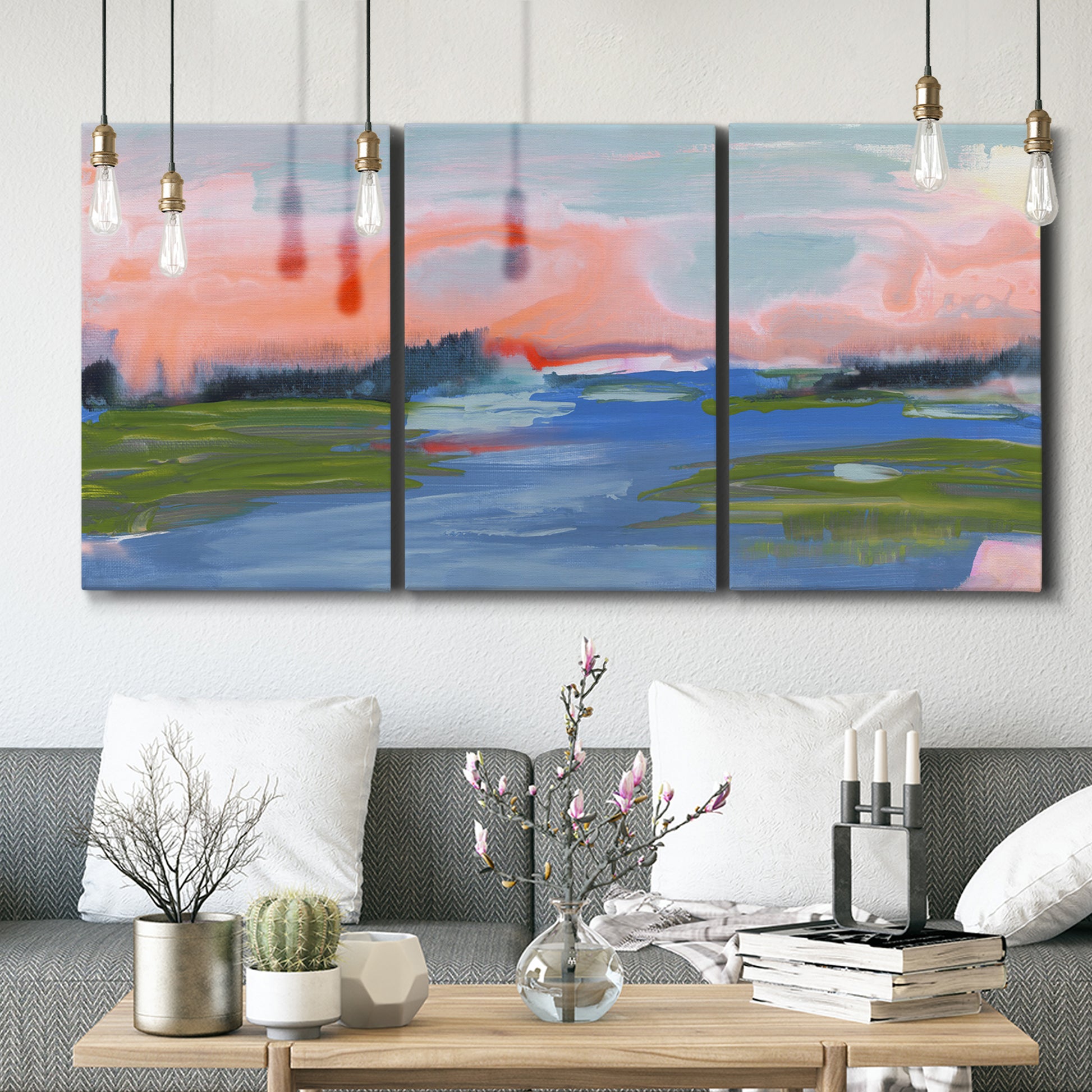 Three-panel canvas wall art featuring sunset reflections across calm sea, displayed in a modern living room above seating.