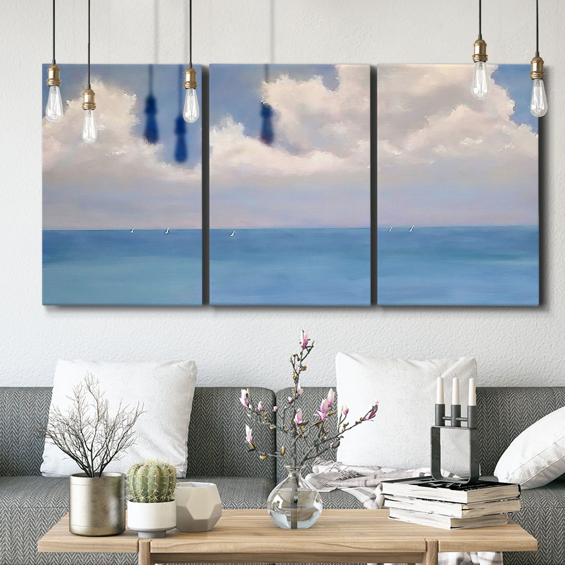 Three-panel canvas wall art featuring coastal shoreline with distant horizon, displayed in a modern living room above seating.