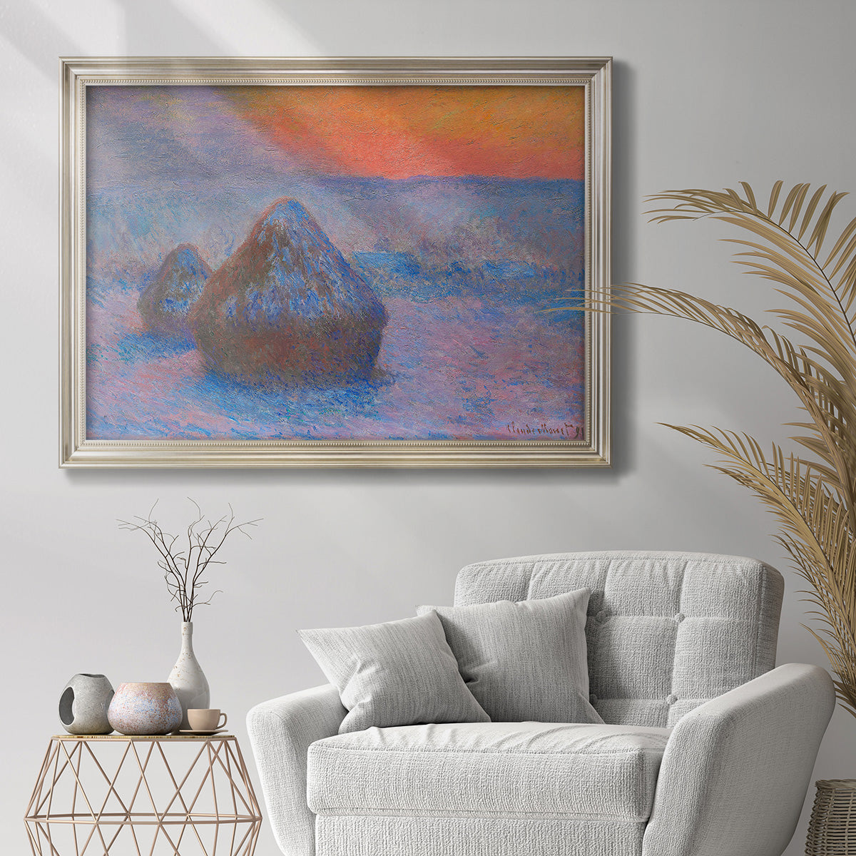 Impressionist haystack scene at sunset by Claude Monet in an ornate champagne frame displayed in a bright interior setting.
